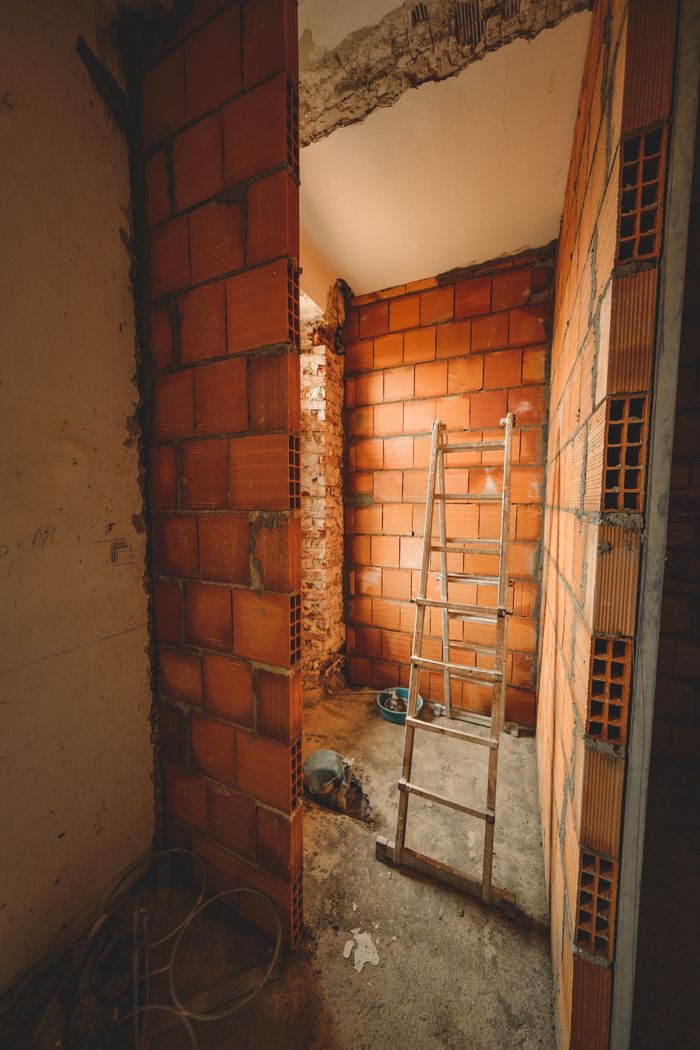 services-03 A construction site with a ladder leaning against red brick walls, showcasing renovation activities.